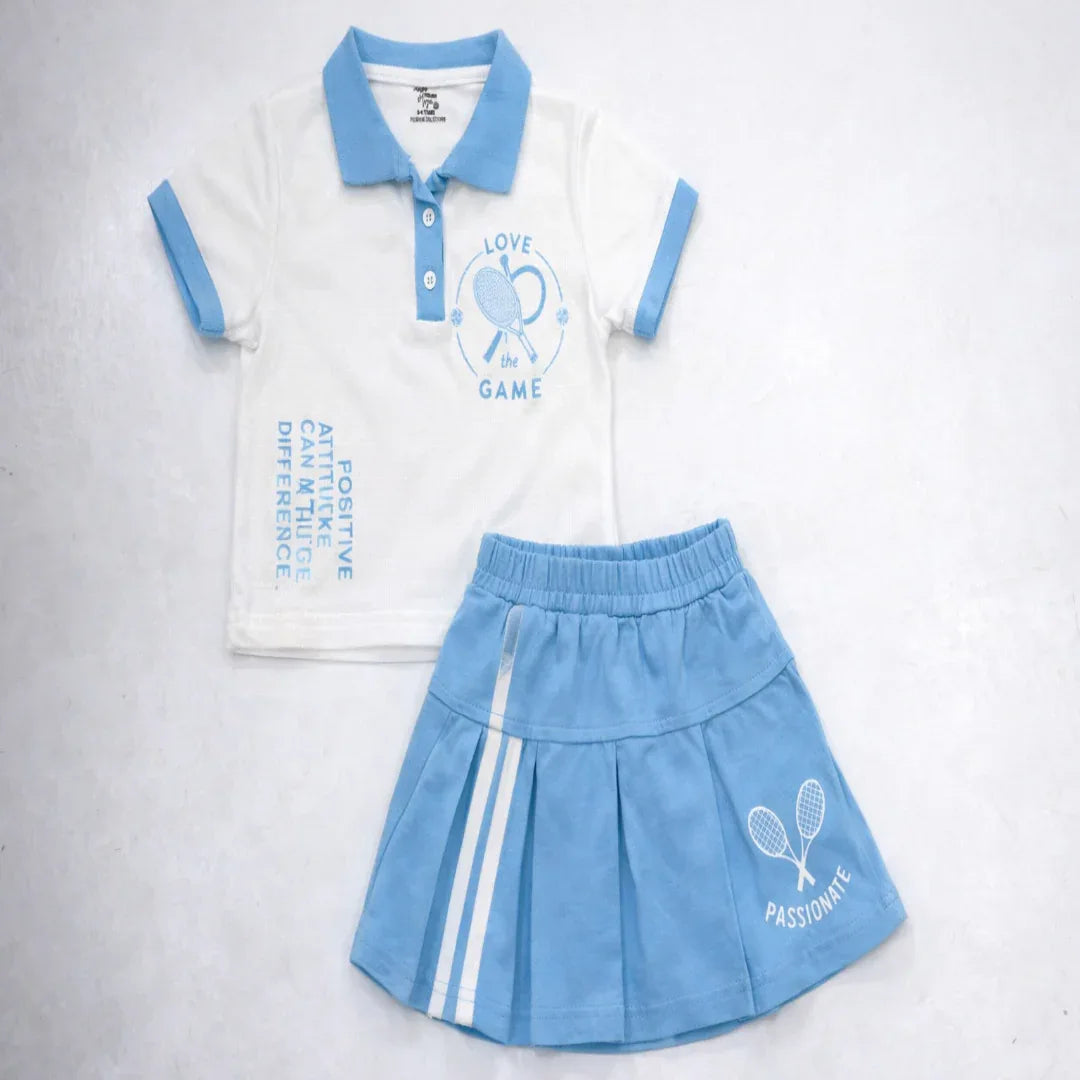 Children's outfit with white polo shirt and blue skirt on a light gray background