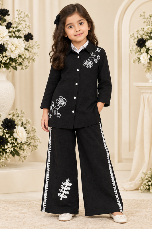 Girl wearing black floral embroidered tunic and black wide-leg pants with white trim