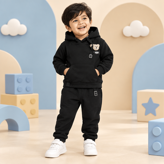 Toddler boy wearing black teddy bear hoodie and jogger set in a playful kidswear studio