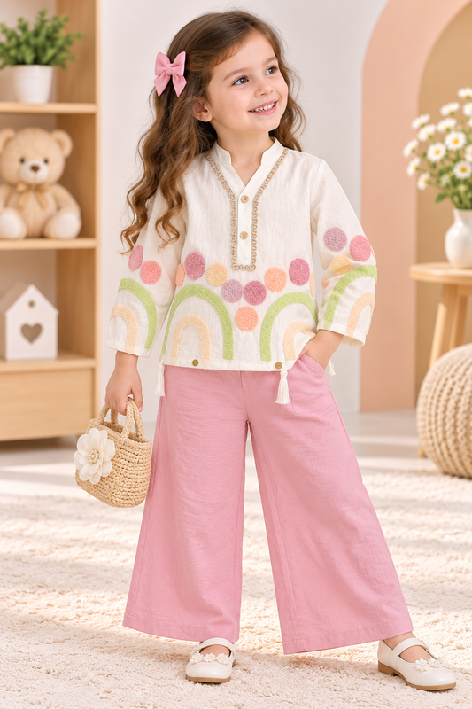 Girl wearing a cream pastel-patterned top with tassel trim and pink wide-leg palazzo pants