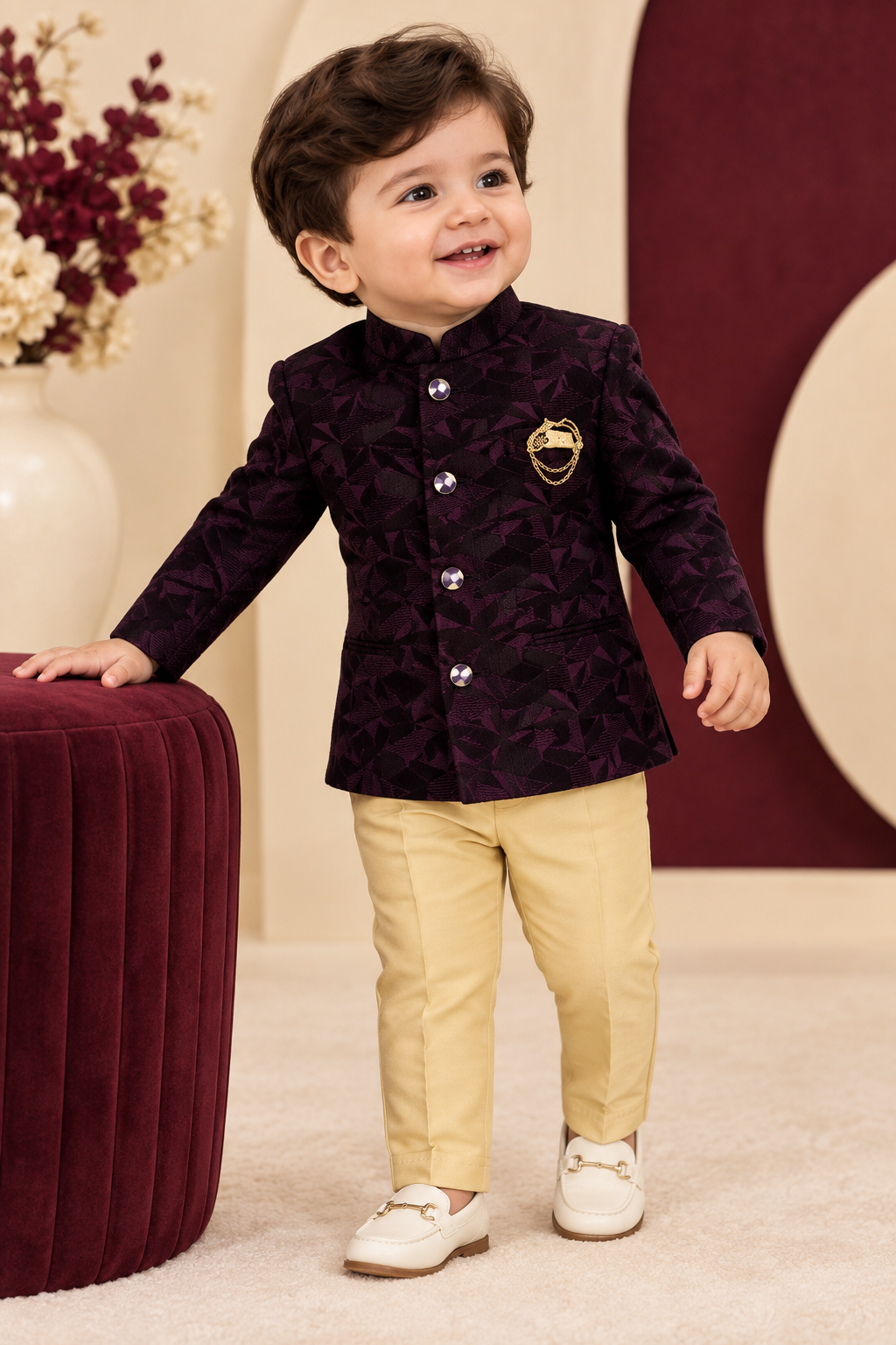 Toddler wearing wine-toned jacket with gold chain detail and beige pants