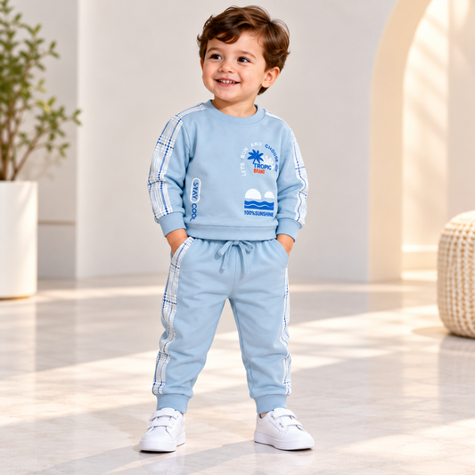 Boy wearing a light blue tropical graphic sweatshirt and matching joggers with checked side panels