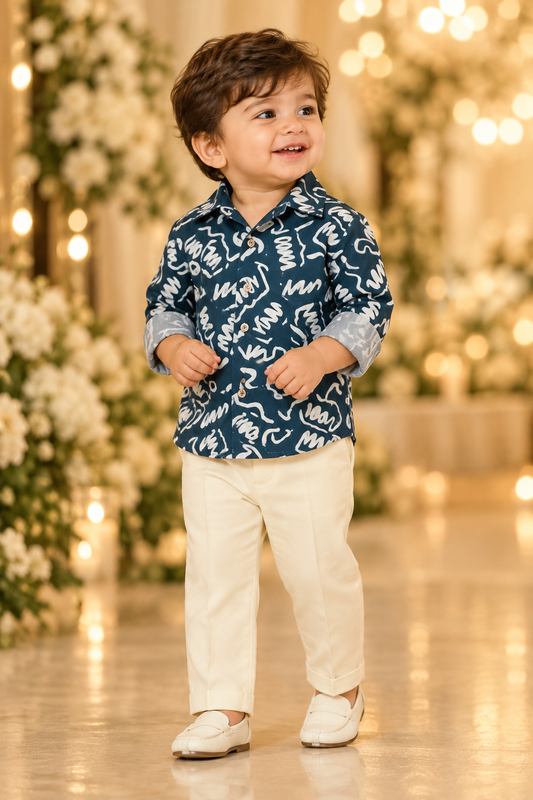 Toddler wearing dark blue-green abstract-print shirt and cream trousers in a reception setting