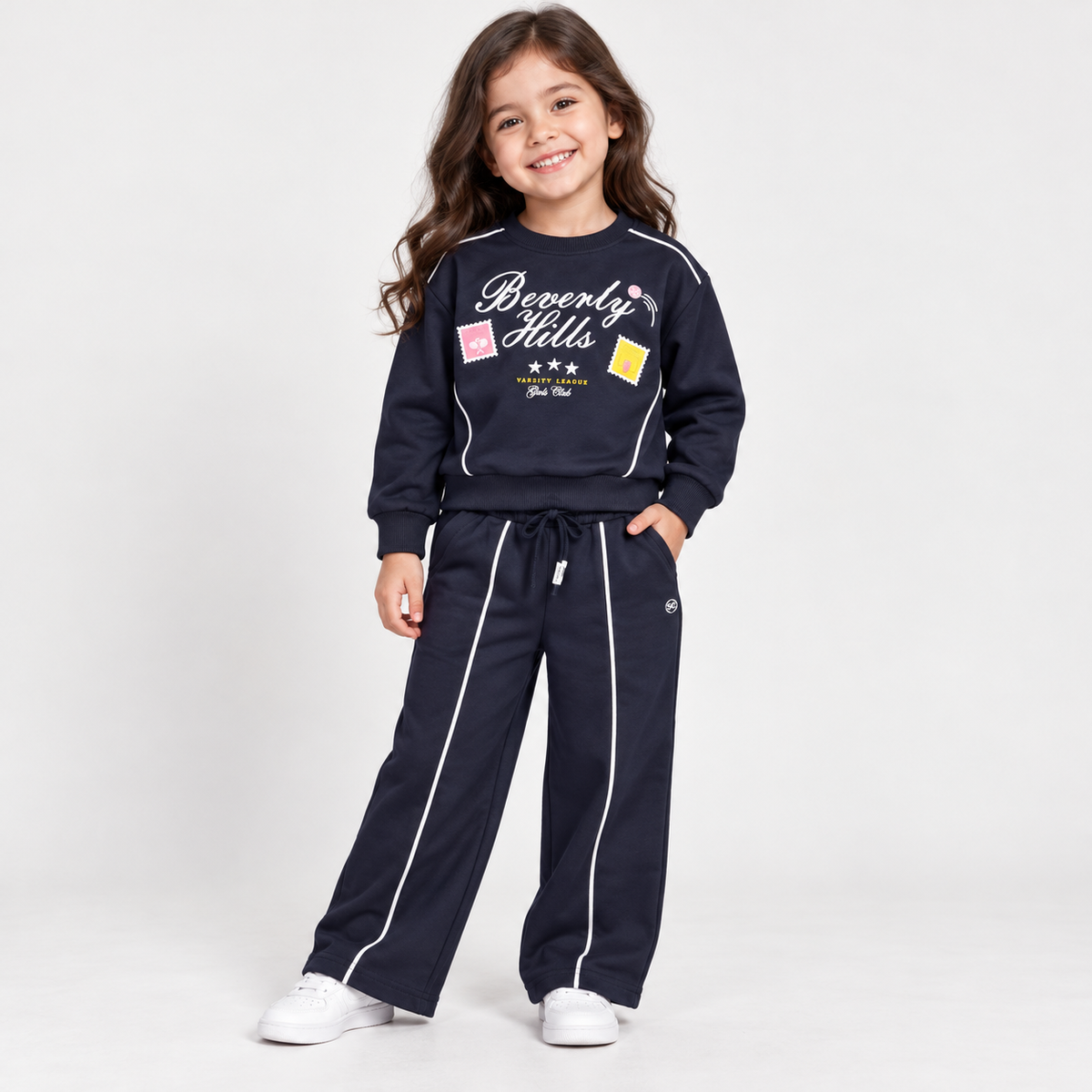 Girl wearing a navy graphic sweatshirt and matching wide-leg pants with white piping